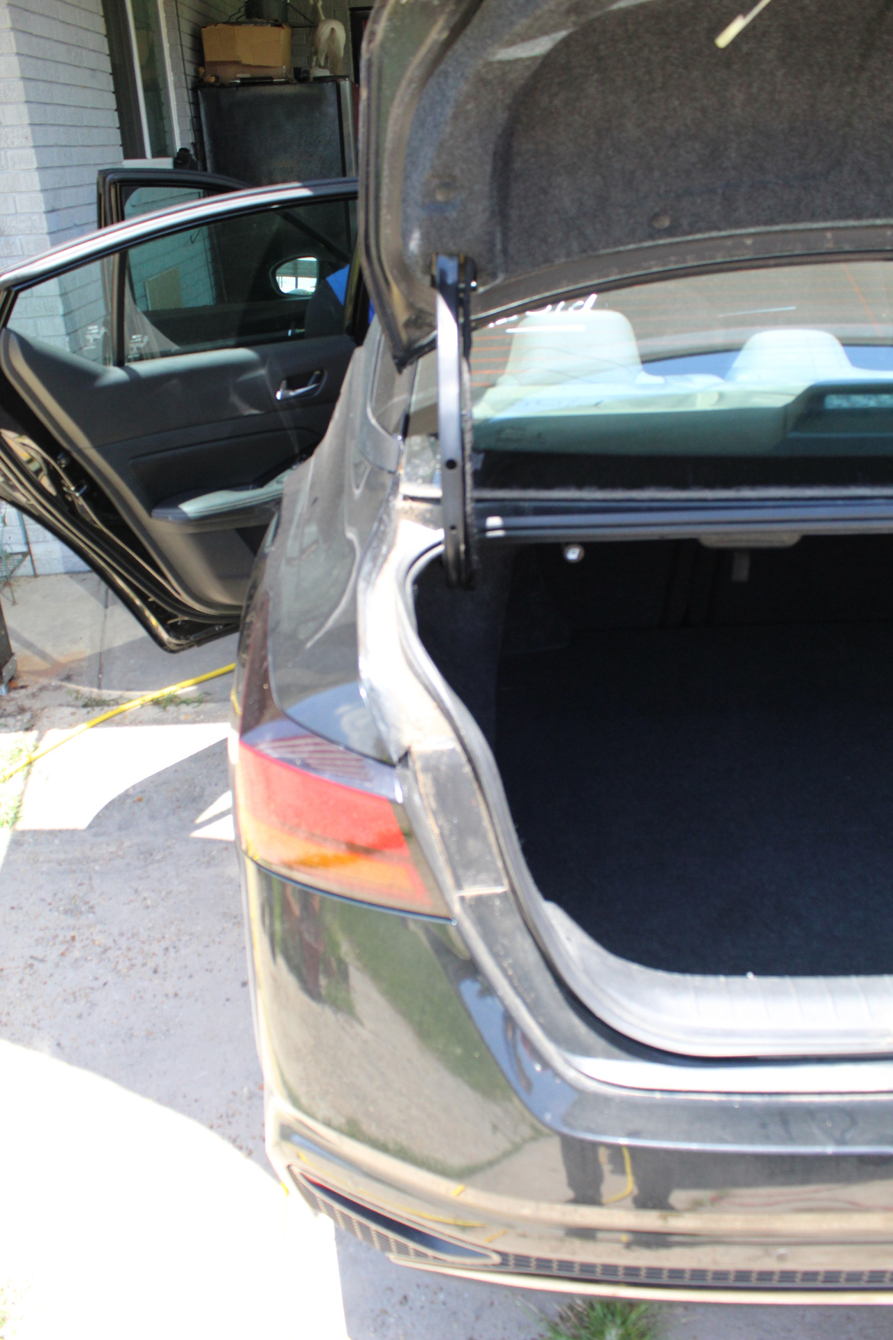 Sedan trunk before detail — dust and debris inside